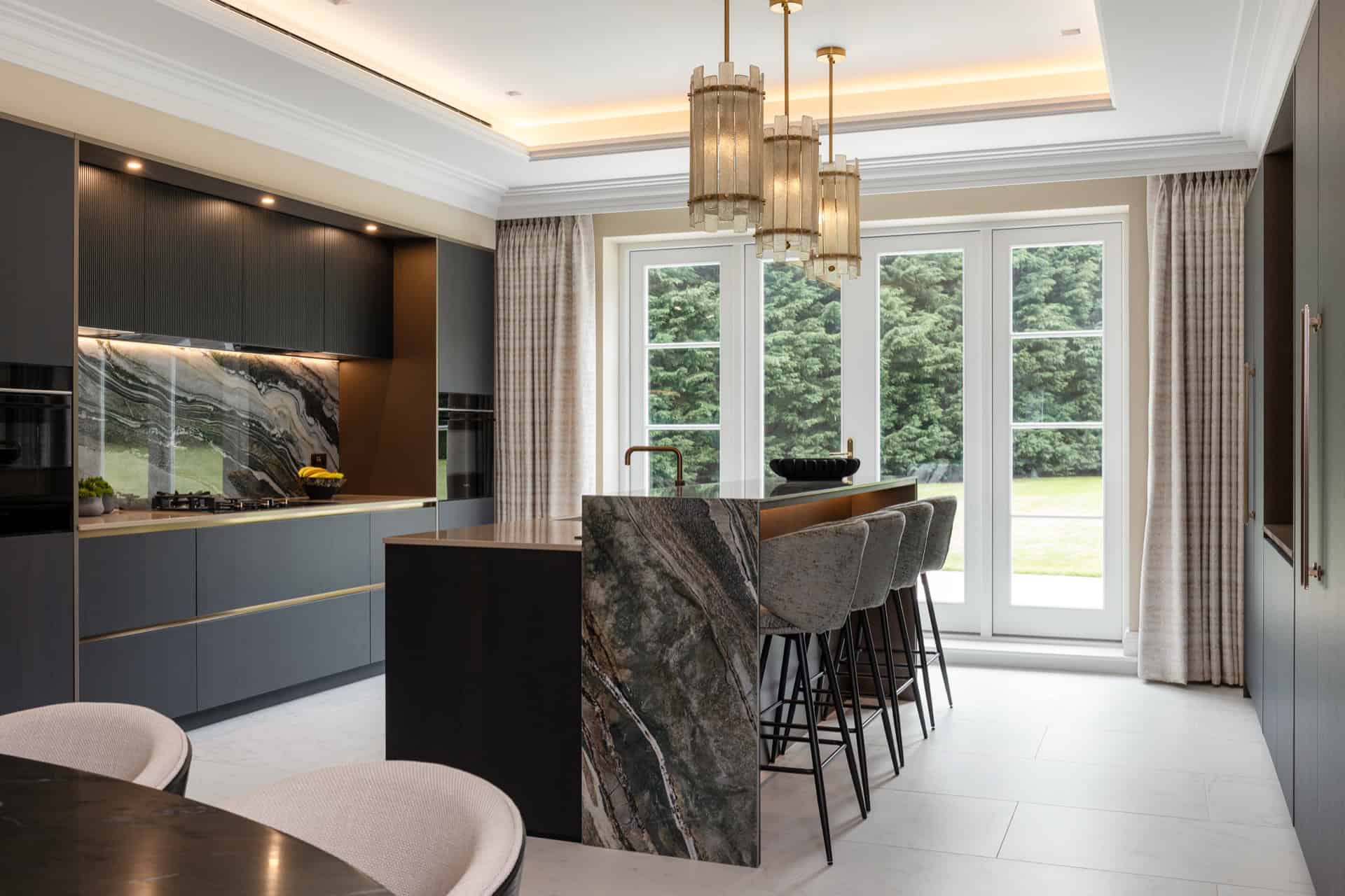 A modern kitchen with marble counter tops and black cabinets.